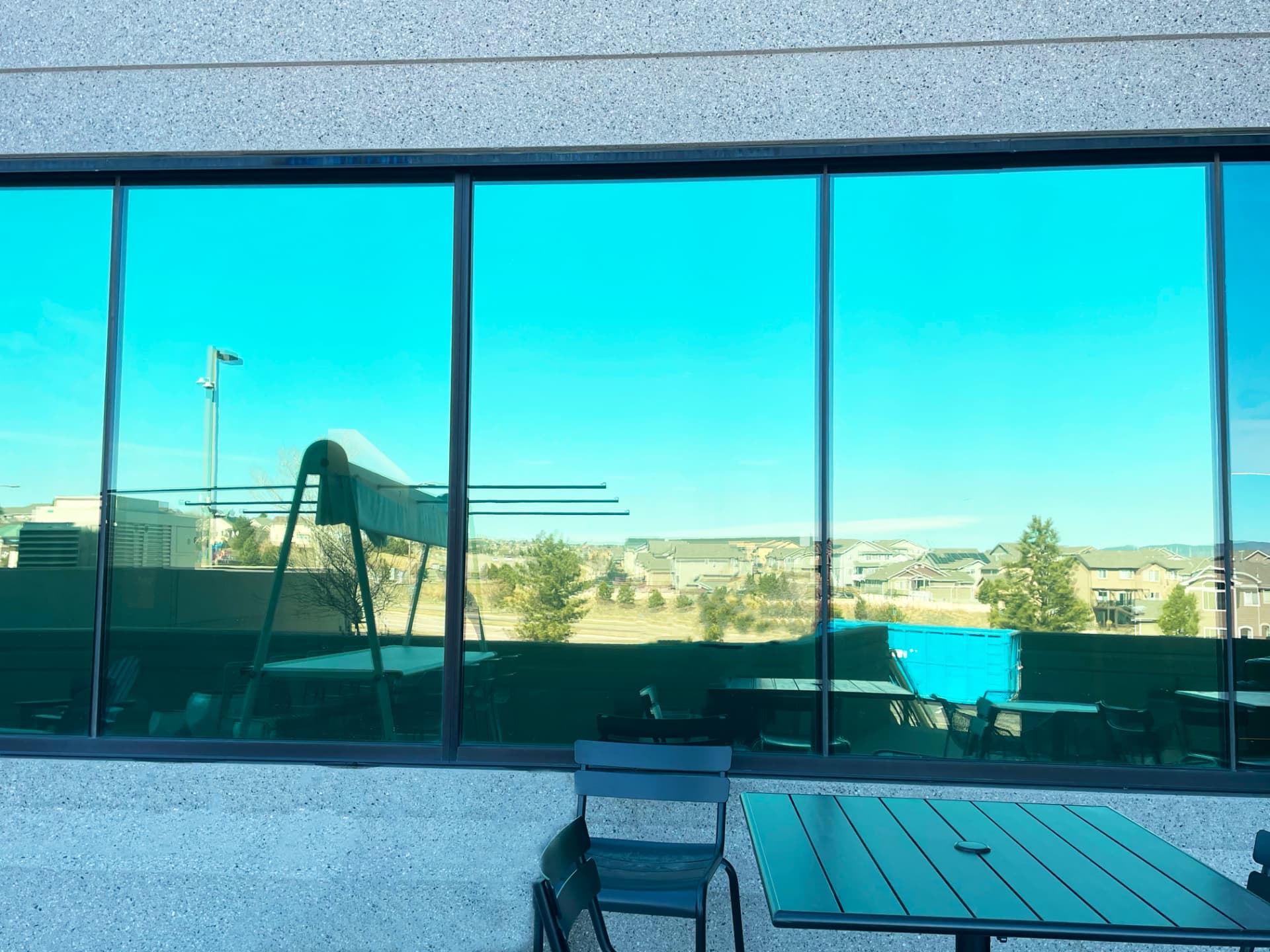 Teal tinted storefront windows beside an outdoor patio