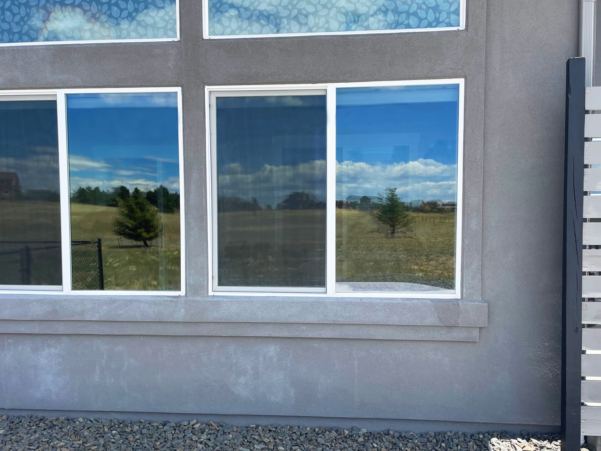 Tinted residential windows on a stucco home reflecting the Colorado landscape